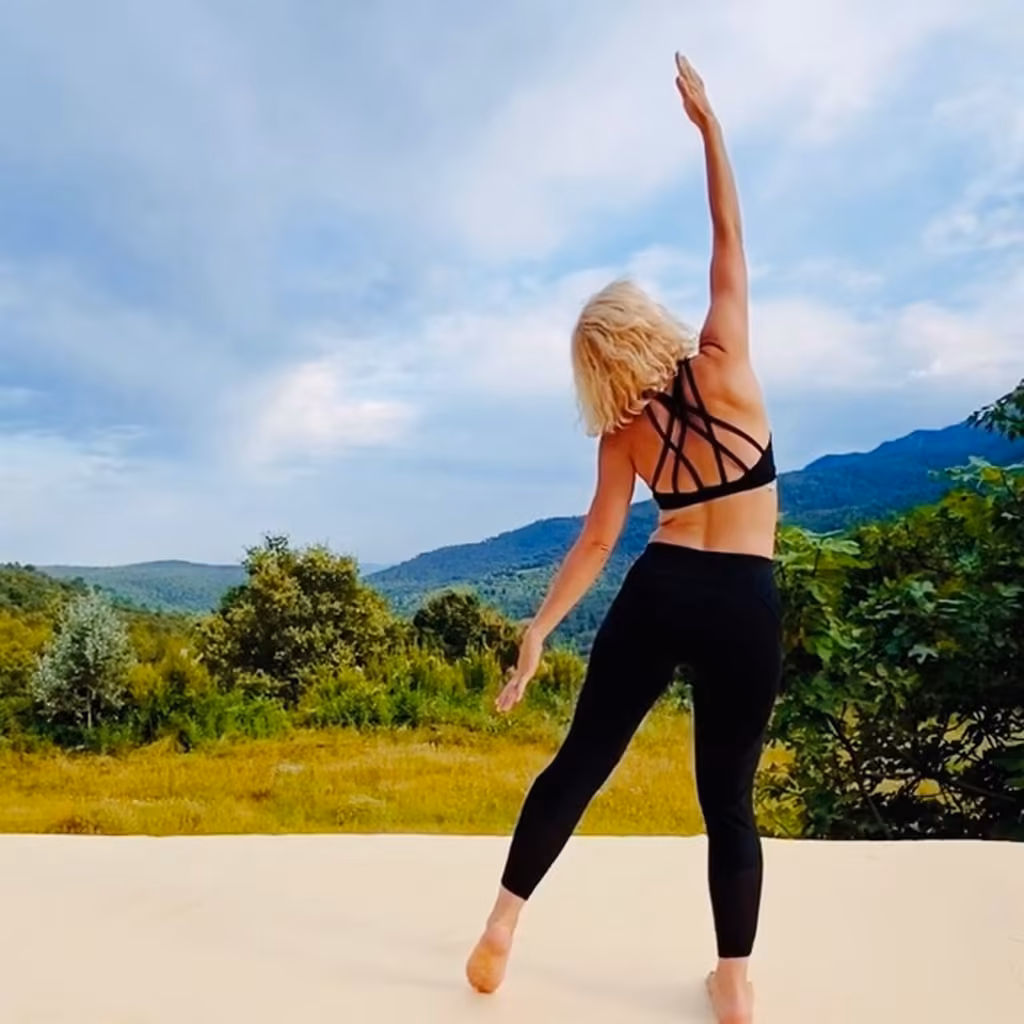 A Flow and Glow student stretching outdoors in the mountains